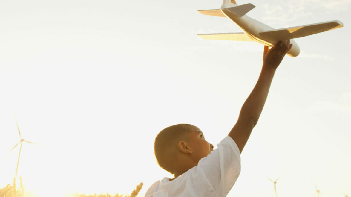 USA, Oregon, Wasco, Boy (10-11) playing with toy aeroplane in wheat field