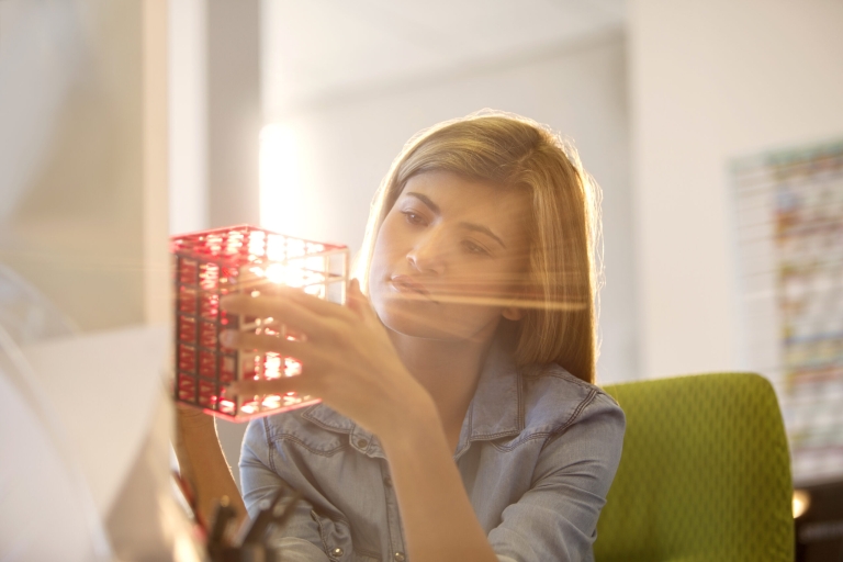 Businesswoman examining cube at desk in office